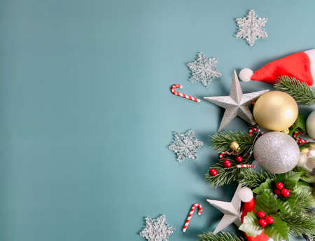 Christmas decorations, pine tree leaves, golden balls, snowflakes, red berries on blue background