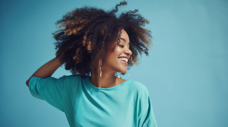 Young curly-haired woman poses happily in front of blue background. Generative AIの素材