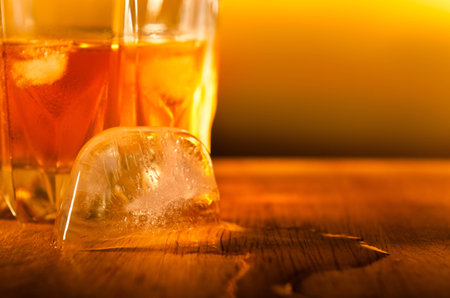 Close up of a ice cube melting away close to a drink in a hot ambient の写真素材