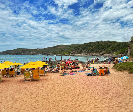 People relaxing on the beach in Horno Beach, Brazil. Sand colored red. Sea, sand and mountains.の写真素材