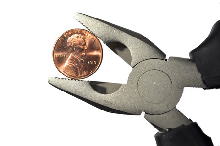 Pair of pliers pinching a shinny pennyの写真素材