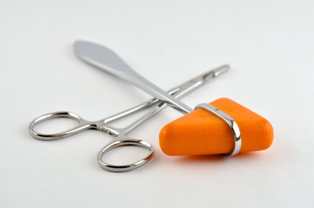 Hemostat and orange reflex hammer with white background
