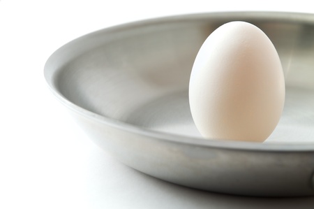 Unbroken egg in a frying pan on a white backgroundの写真素材