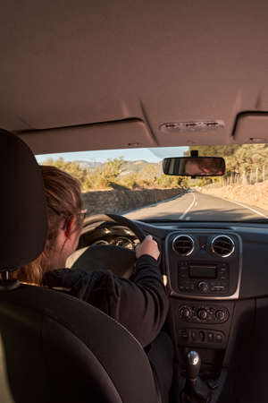 unrecognizable blonde woman driving a car on the roadの写真素材