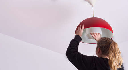 unrecognizable blonde woman changing a light bulb at home, DIY.