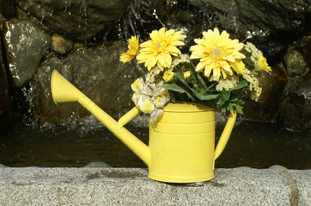 YELLOW WATERING CAN WITH FLOWERSの写真素材