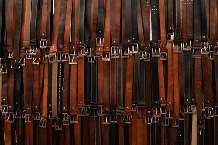 Stylish brown background, wallpaper aesthetics, shot of several elegant leather belts in a market...