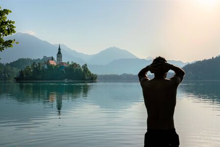 Silhouette of an European man doing morning stretches after practicing the method of meditation and deep breathing Wim Hof , while bathing in lake Bled.の写真素材