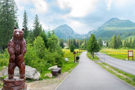 Vysoke Tatry, High Tatras / Slovakia - June 18, 2018: Wooden statue of a bear on a road with mountains in the background.のeditorial素材