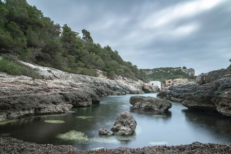 Cala s'Almunia, in Santanyi, Majorca. Landscape long exposure shot of an empty inlet cove with pine trees and lot of posidonia oceanicaの写真素材
