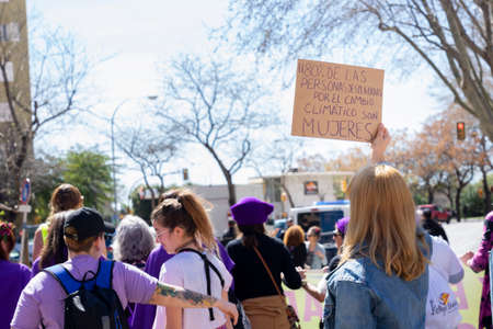 Palma de Mallorca, Spain - March 08, 2020: International Women's Day. Blonde girl with a banner in the feminist protest, in the banner: El 80% DE LAS PERSONAS DESPLAZADAS POR EL CAMBIO CLIMATICO SON MUJERES.のeditorial素材