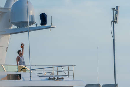 Calvia, Majorca, Spain - June 1, 2020: man lifting weights and exercising on his private yacht, moored in Port Adrianoのeditorial素材