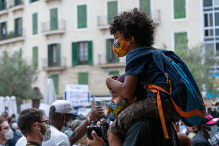Palma, Majorca, Spain - June 7, 2020: photographer during the demonstration against racism, with his son piggybackのeditorial素材