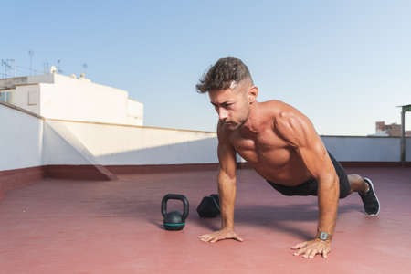 Athletic and muscular man doing push-ups during a fitness session on the terrace of his homeの写真素材