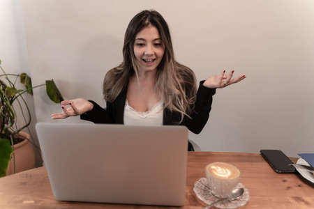 Pretty elegant businesswoman gesturing with hands on video call or virtual meeting at breakfast and coffee timeの写真素材