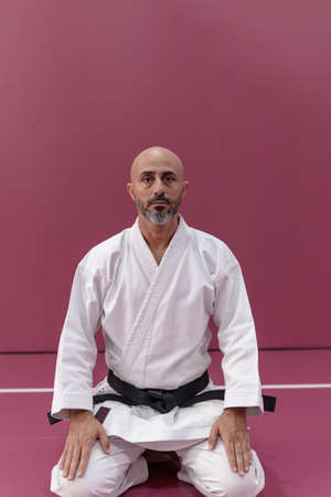 Karate master sitting in meditation pose, back turned, in his dojo or martial arts schoolの写真素材