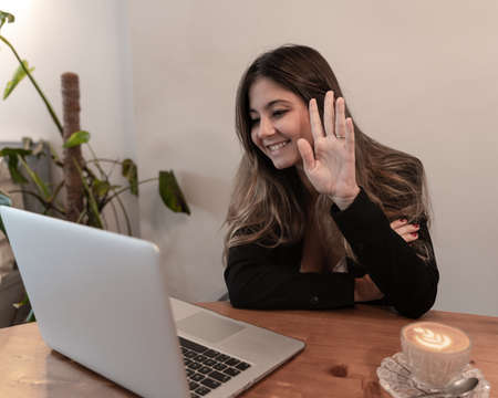 Pretty elegant businesswoman gesturing with hands on video call or virtual meeting at breakfast and coffee timeの写真素材