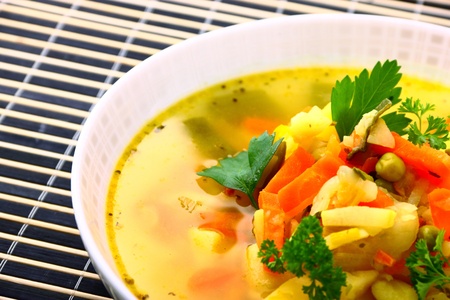 Fresh vegetable soup made of carrot, potato, leek, parsley, pea and bean in bowlの写真素材