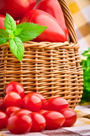 Wicker basket full of fresh tomatoes and cherry tomatoesの写真素材