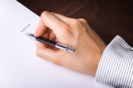 Human hand with pen signing a documentの写真素材