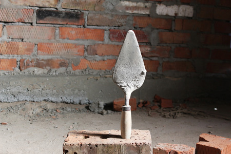 Trowel on a brick wall backgroundの写真素材