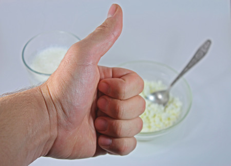 Thumbs up man's hand on the background of cottage cheese and kefirの写真素材