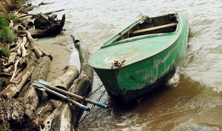 Old green boat with oars on the coast