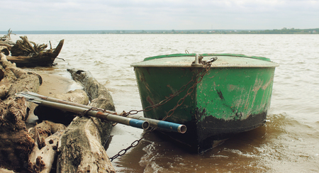 Old green boat with oars on the coastの写真素材