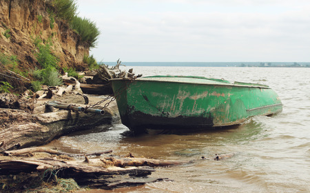 Old green boat with oars on the coastの写真素材