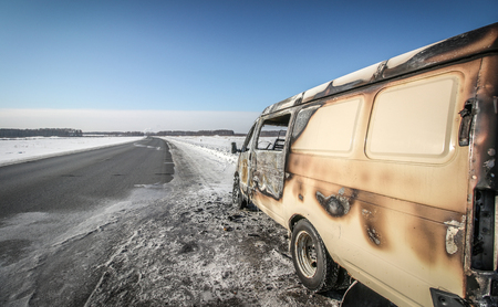 Lonely burnt car on a suburban highway in the winterの写真素材