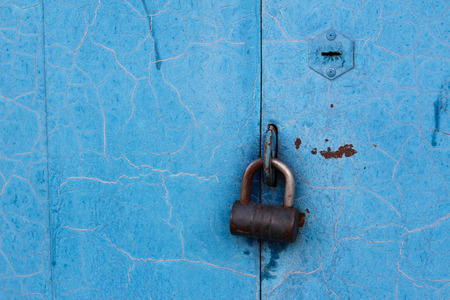 Old lock on a chain on an blue iron doorの写真素材