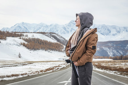 Girl on the background of mountains in winterの写真素材