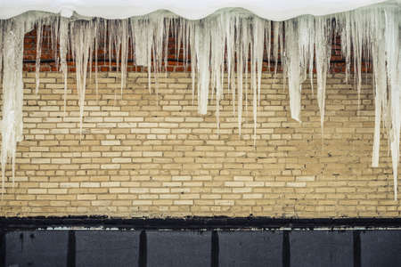 Background - old shabby brick wall with iciclesの写真素材