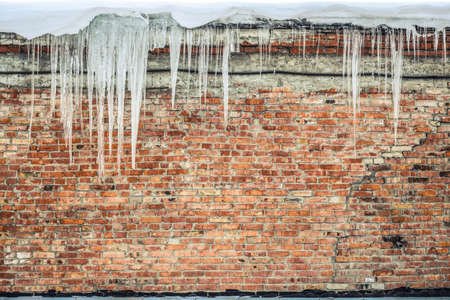 Background - old shabby brick wall with iciclesの写真素材