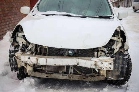 Disassembled damaged car after an accident on the street. Deformed hood. Without headlights and bumperの写真素材