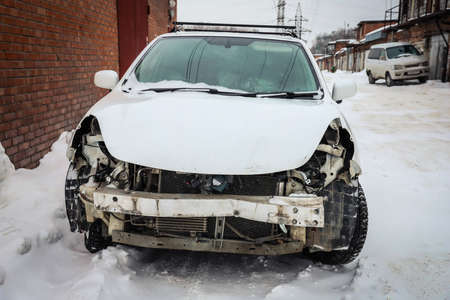 Disassembled damaged car after an accident on the street. Deformed hood. Without headlights and bumperの写真素材