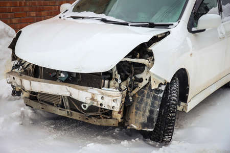 Disassembled damaged car after an accident on the street. Deformed hood. Without headlights and bumperの写真素材