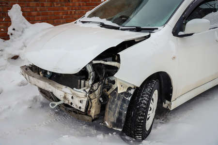 Disassembled damaged car after an accident on the street. Deformed hood. Without headlights and bumperの写真素材