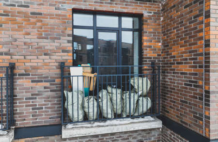 Bags with construction debris on a small balcony close-up. brick houseの写真素材