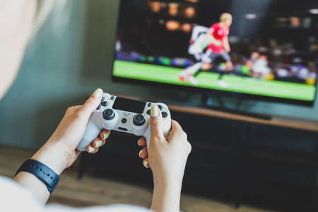 Girl playing a video game console. Game is football. Joystick in hand. selective focusの写真素材