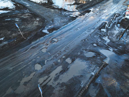 Broken old asphalt road outside the city. Pits and potholes. Aerial view