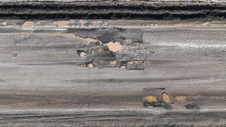 Broken old asphalt road outside the city. Pits and potholes. Aerial viewの写真素材