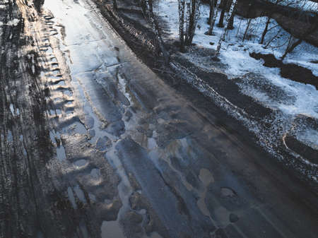 Broken old asphalt road outside the city. Pits and potholes. Aerial viewの写真素材