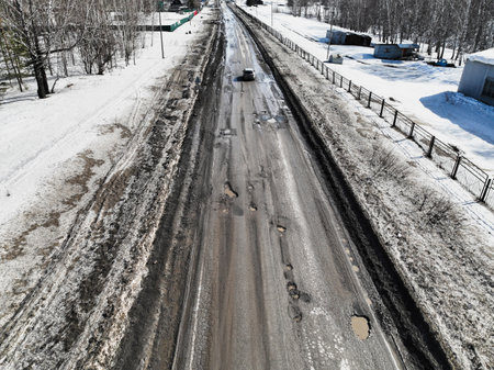 Broken old asphalt road outside the city. Pits and potholes. Aerial viewの写真素材