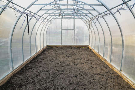 The empty greenhouse before planting. Plowed earthの写真素材