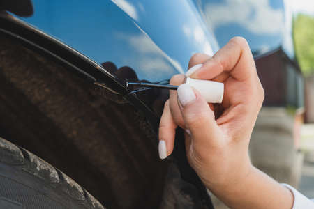 Touching up a body car with a small brush by a young womanの写真素材