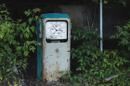 Old rusty abandoned gas station overgrown with grass and treesの写真素材