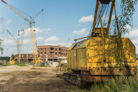 The disassembled old crawler crane on the background of a construction site