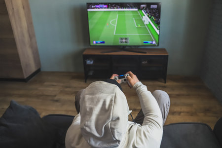 Guy playing a video game console. Game is football. back view. selective focusの写真素材