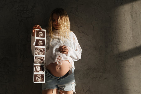 Portrait of a pregnant girl with an ultrasound scan in her hands. beautiful natural lightの写真素材